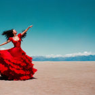Woman in flowing red dress dancing on barren desert plain with mountains in the distance