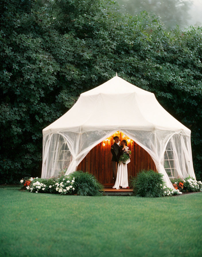 Newlywed Couple Embraces in Canopied Tent Amid Lush Greenery