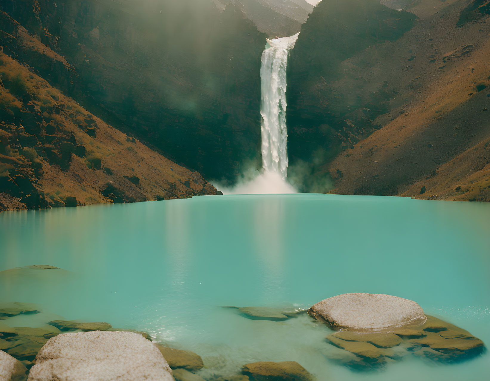 Serene turquoise lake with cascading waterfall and rugged cliffs