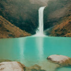 Serene turquoise lake with cascading waterfall and rugged cliffs