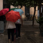 Individuals with umbrellas on a rainy street at night.