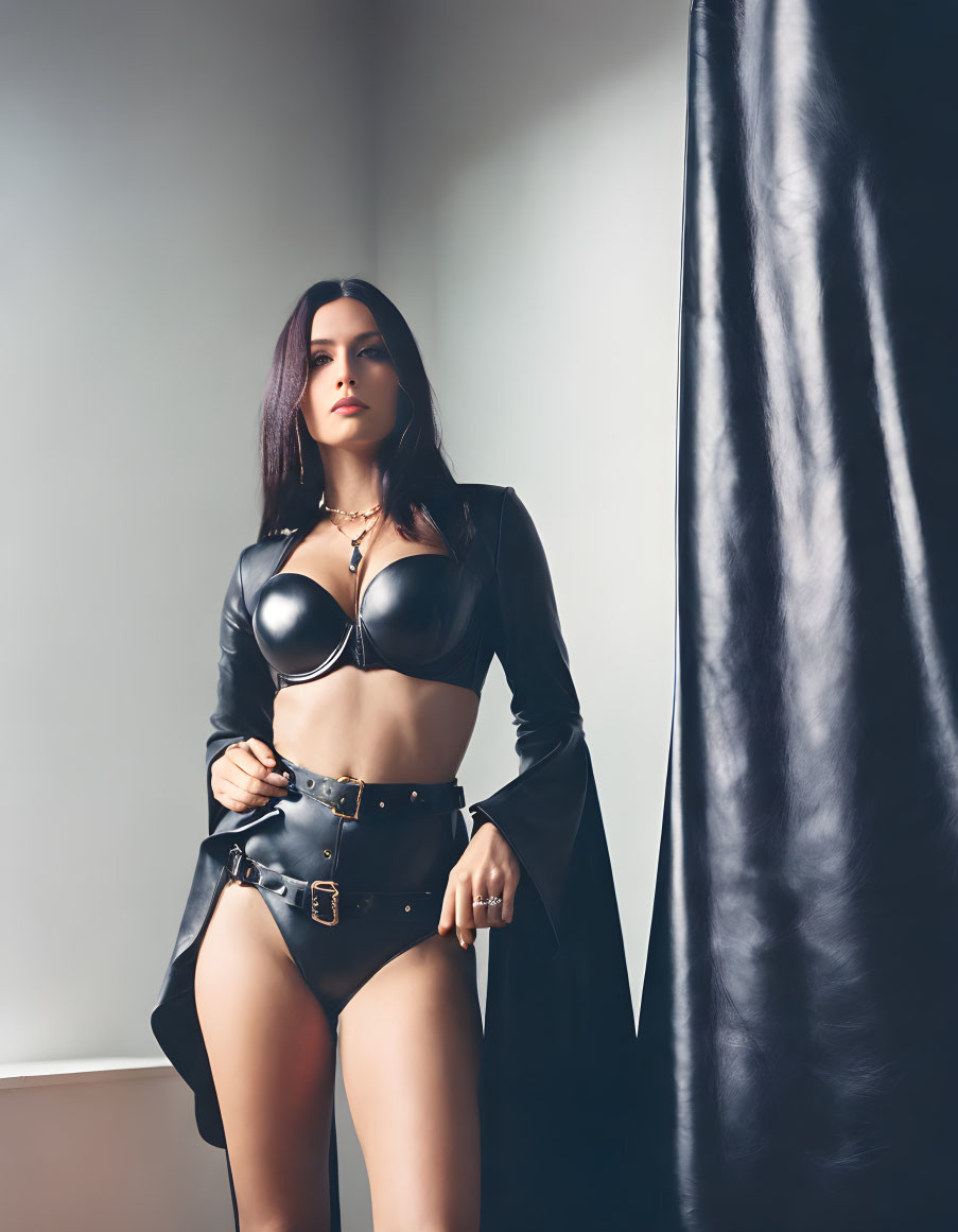 Confident Woman in Black Leather Outfit Beside Curtain