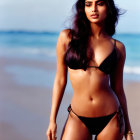 Woman in black bikini on beach with flowing hair and ocean backdrop