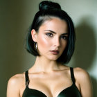 Dark-haired woman in bun and hoop earrings against neutral backdrop