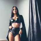 Confident Woman in Black Leather Outfit Beside Curtain