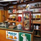 Victorian woman in dress at well-stocked potion shop with jars, bottles, and fruits