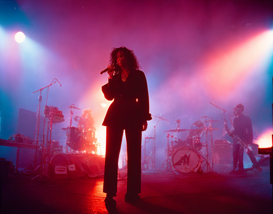 Curly-Haired Singer Performs on Stage with Band in Background