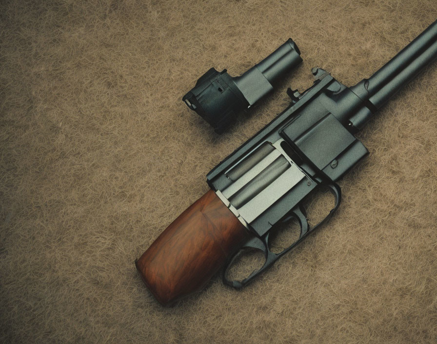 Wooden-grip revolver with large barrel on textured surface with detached speedloader