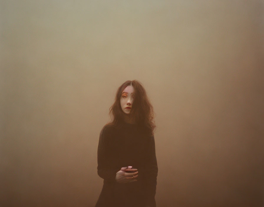 Long-Haired Person in Dark Sweater Against Foggy Background