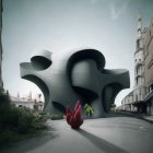 Pink-coated person views modern black building with cube structures and hedges against historic backdrop under clear sky