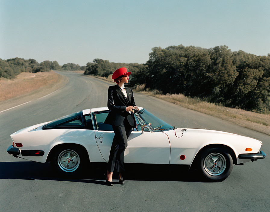 Woman in Red Hat Stands by Vintage Car on Empty Road