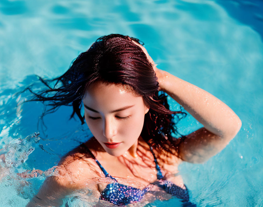 Woman with Wet Hair Emerging from Blue Pool Under Sunlight