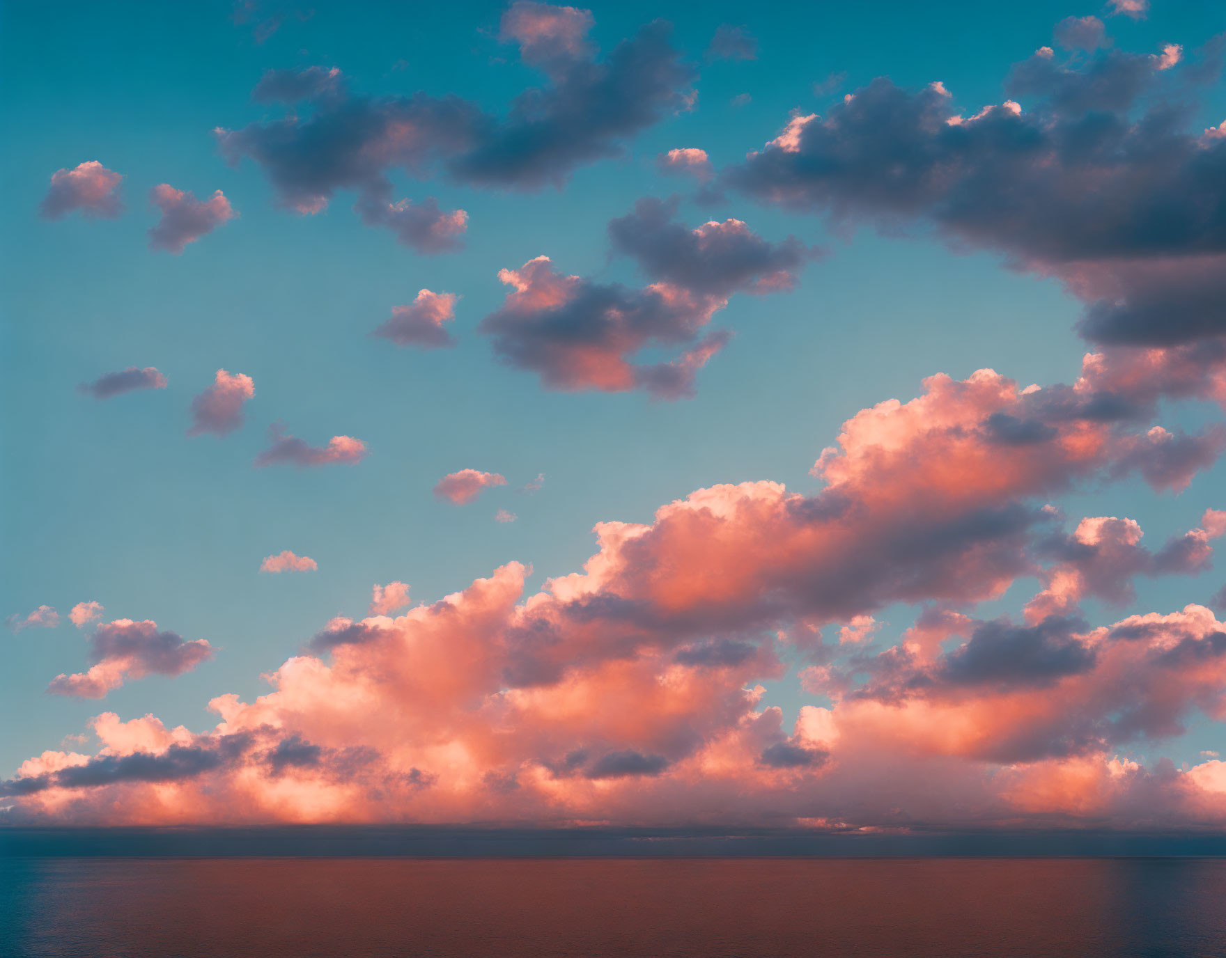 Tranquil seascape with pink and orange clouds over calm blue ocean