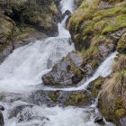 Tranquil waterfall flowing over mossy rocks in lush forest