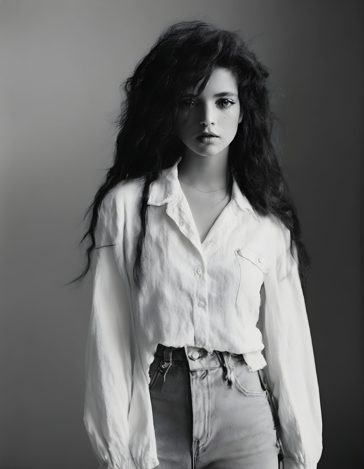 Monochrome portrait of woman with voluminous hair in white shirt and jeans