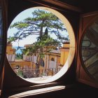 Round window showcasing vibrant village with golden domes and autumn trees.