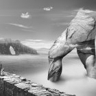 Monochrome fantasy landscape with rock formations, trees, figure, and multiple moons