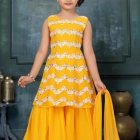 Young girl in yellow dress with floral embroidery against floral backdrop