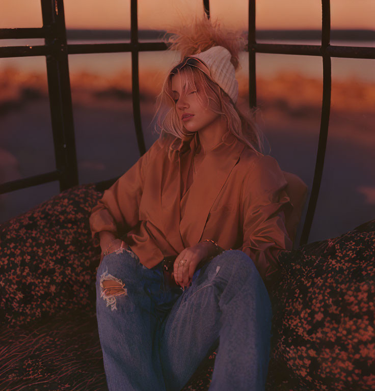 Relaxed person at sunset in beanie, torn jeans & oversized shirt