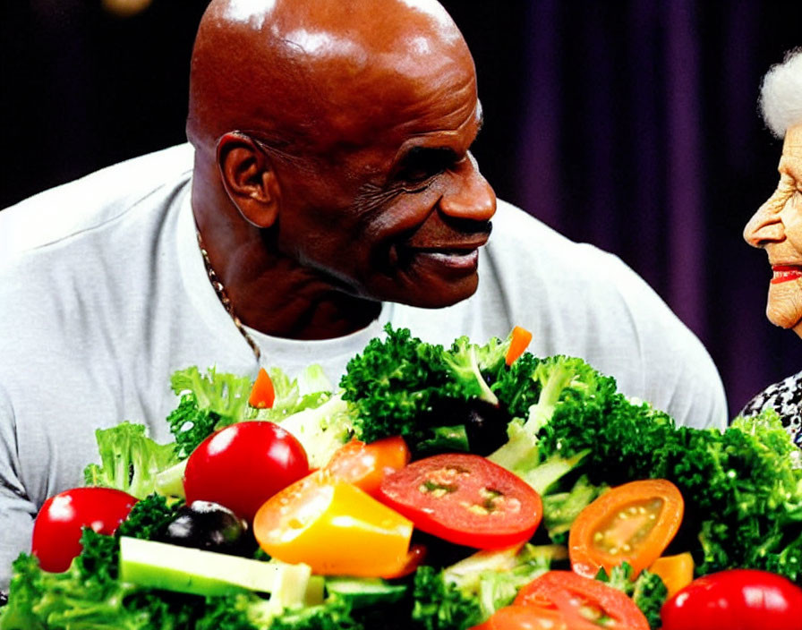 Bald man smiles at elderly woman with colorful salad