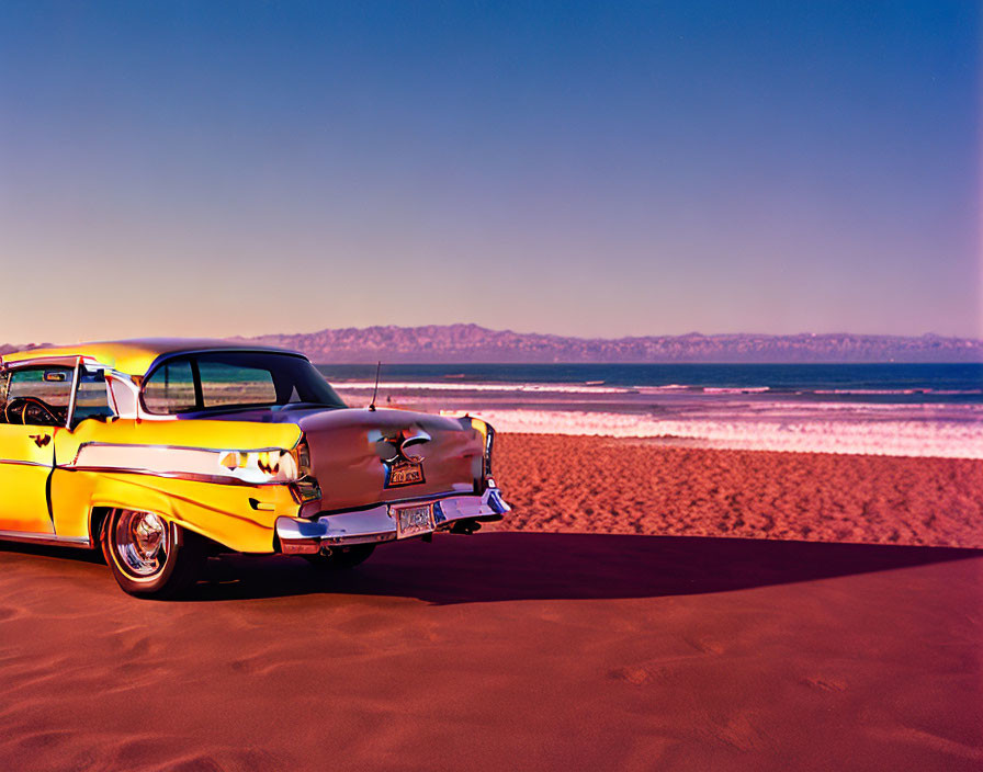 Yellow classic car on sandy beach with ocean and blue sky at sunrise/sunset