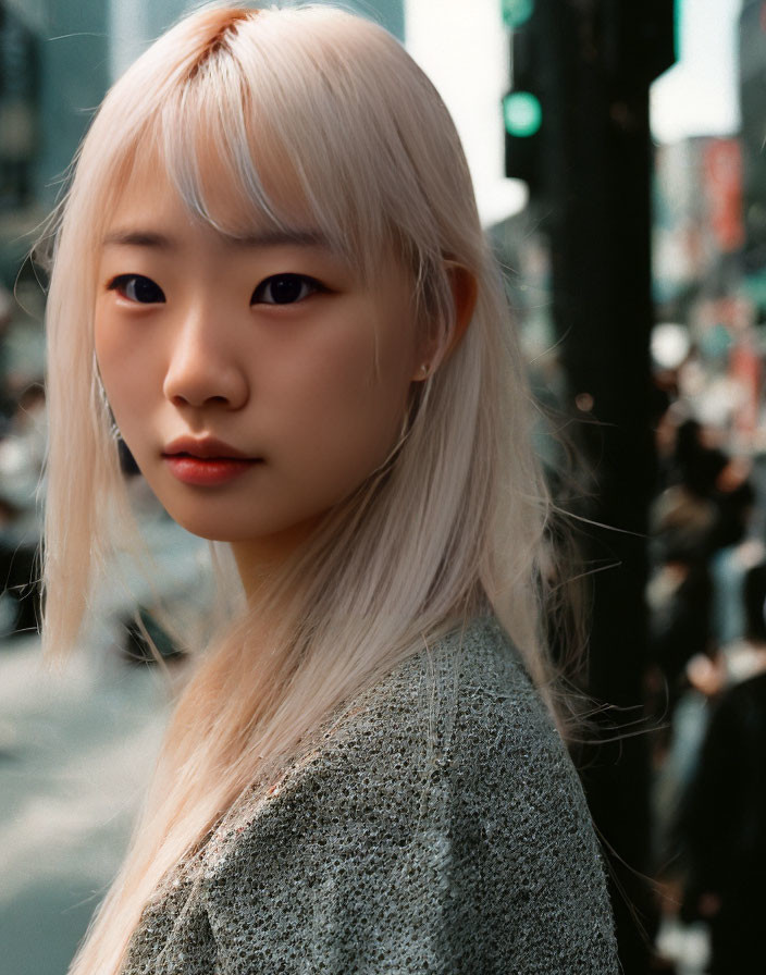 Blonde woman in grey sweater on busy street