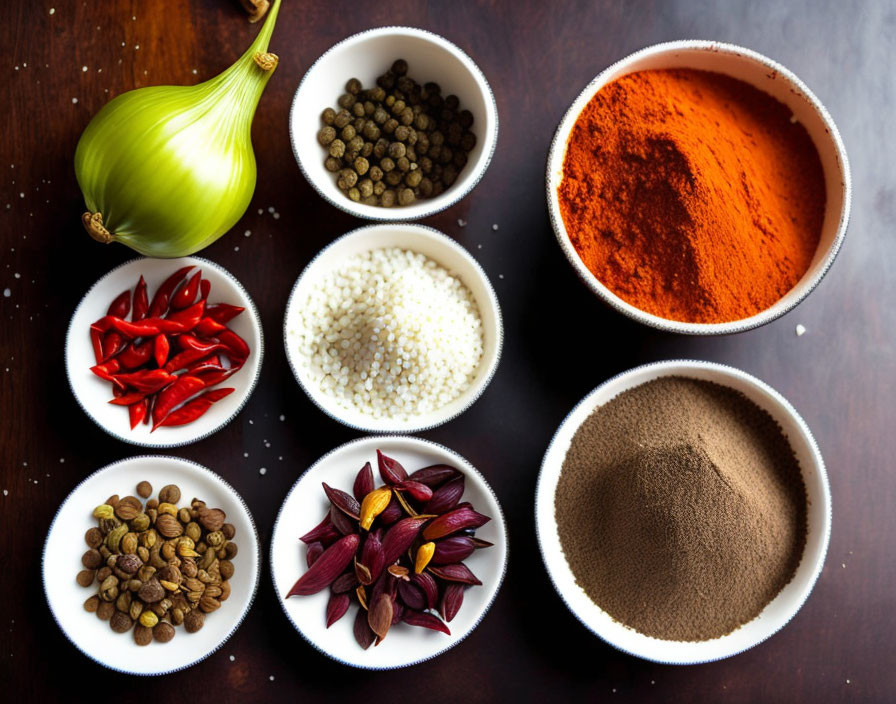 Various spices and onion on wooden surface: red chilies, coriander seeds, peppercorns