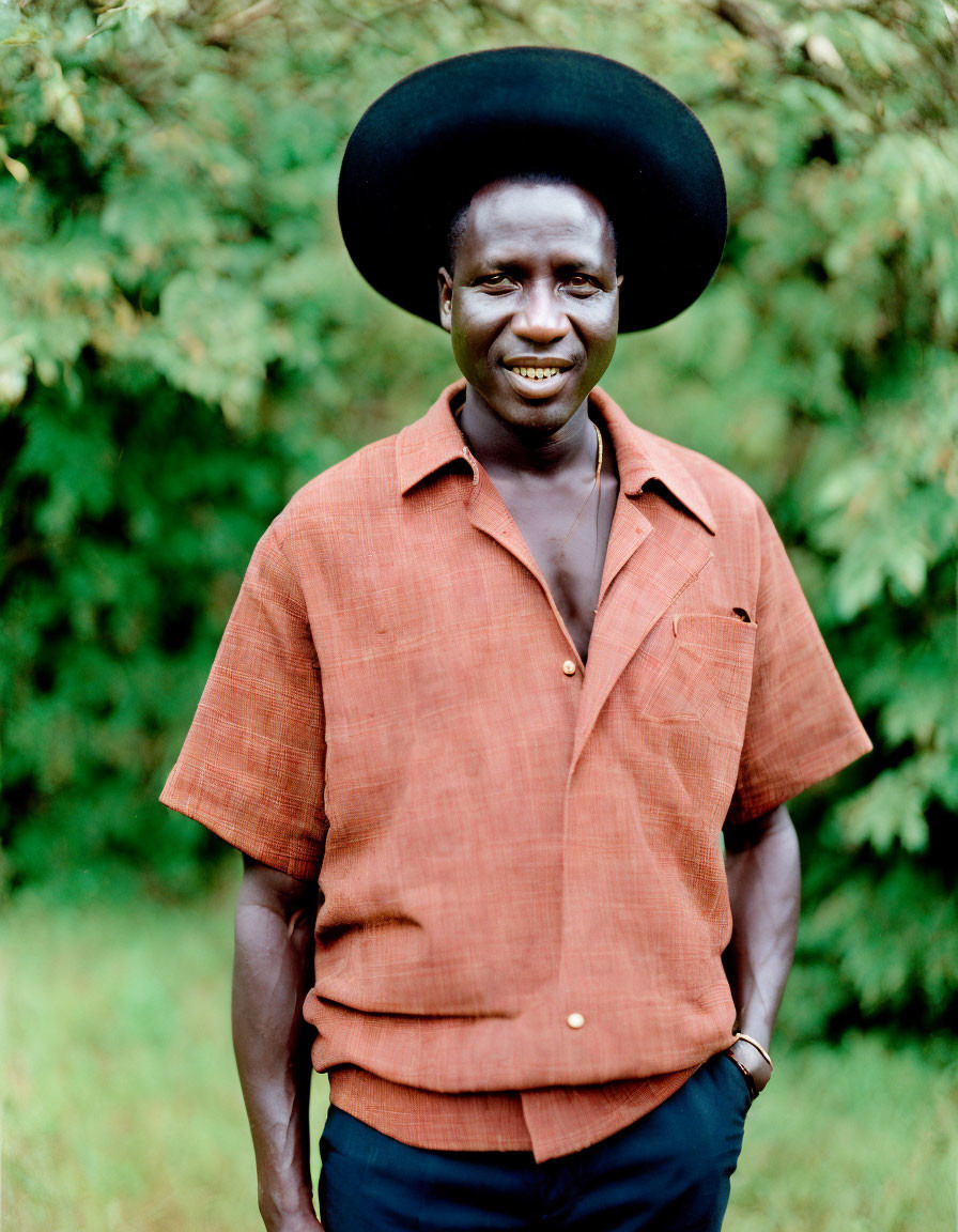 Man in Black Hat Smiling Against Green Background