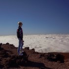 Person on Cliff Edge at Sunset Overlooking Cloud Sea & Airships