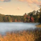 Tranquil morning fog over still lake with autumn trees and boat