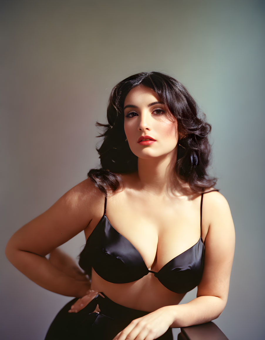 Dark-haired woman in black top exudes classic glamour against neutral backdrop