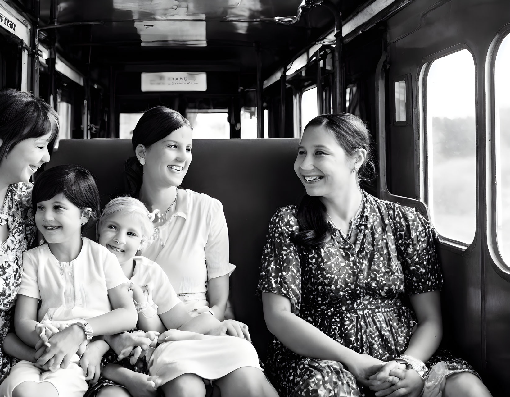 Vintage black and white photo: Smiling women and children in train carriage