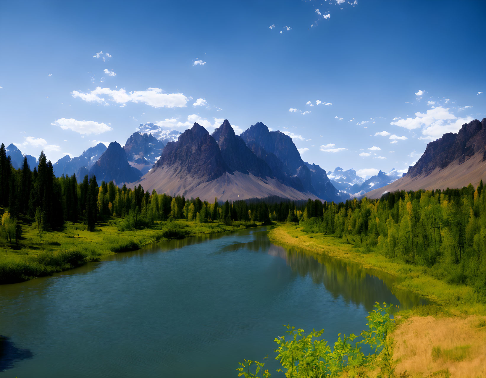 Scenic river in lush valley with sharp mountains