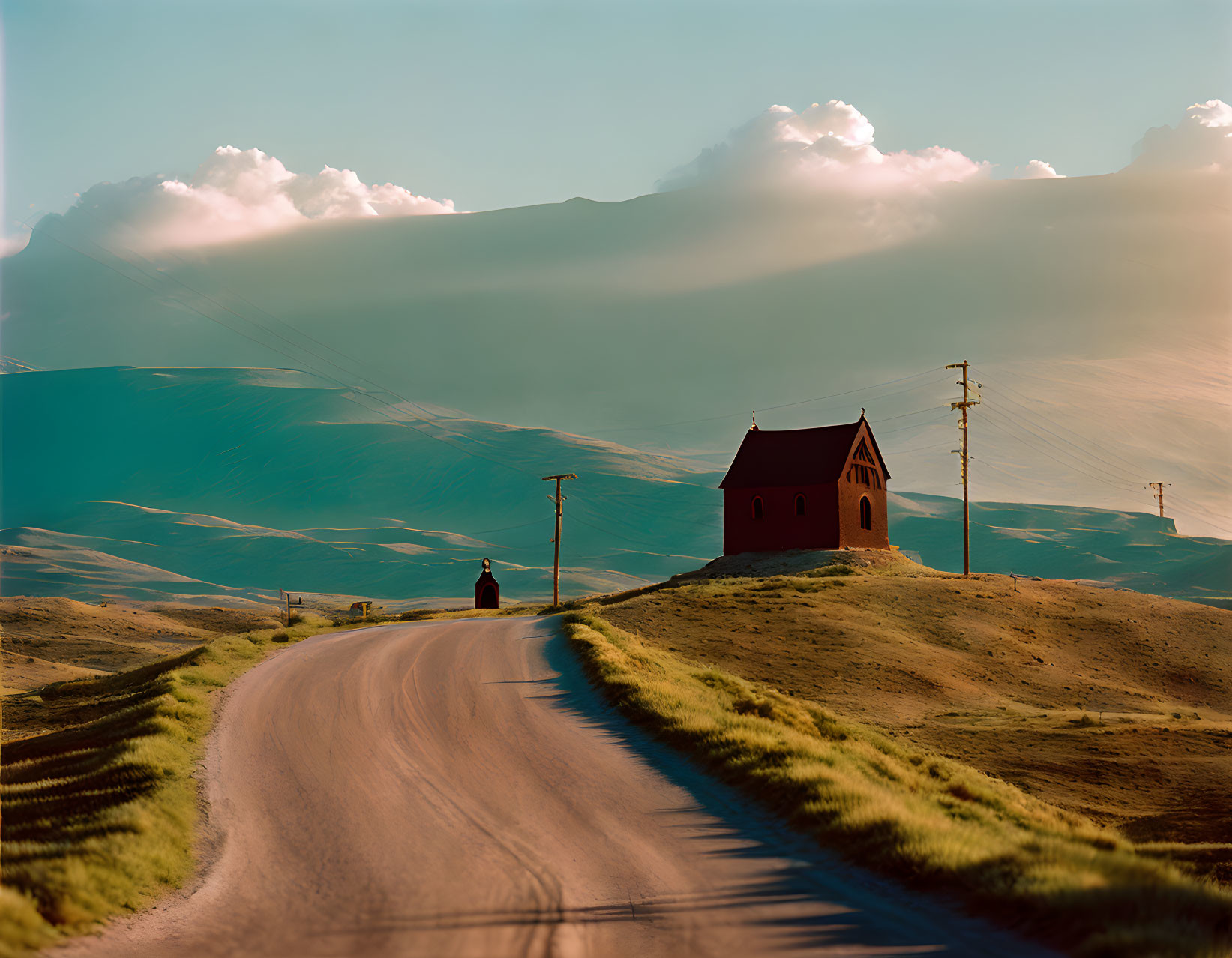 Solitary figure walking towards small red church under vast sky