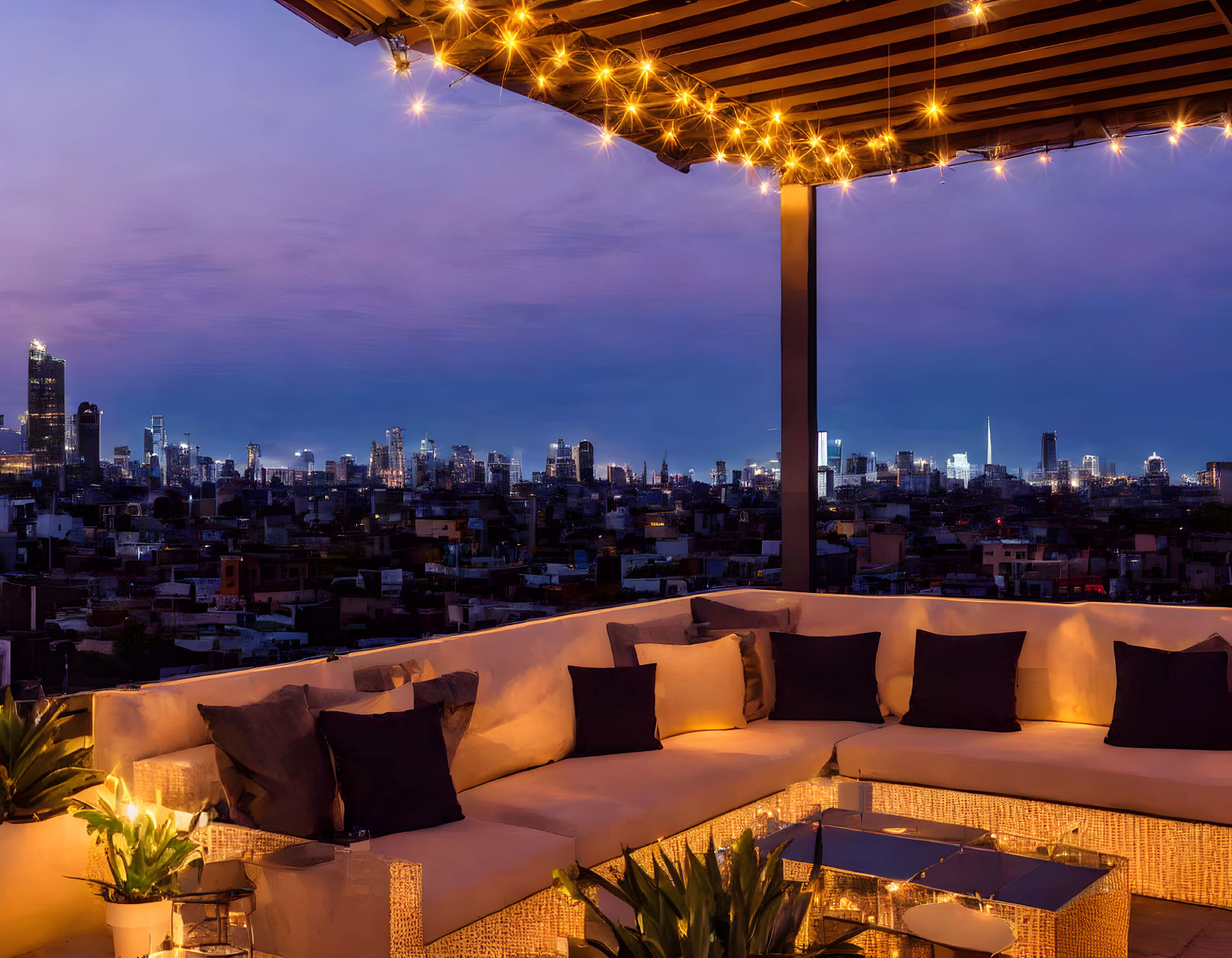 White sofa and string lights on rooftop terrace with city skyline view