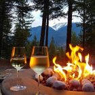 Wine glasses by campfire with mountain view at dusk