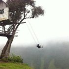 Warrior on grassy hill gazes at misty valley with mountains, treehouse, and birds