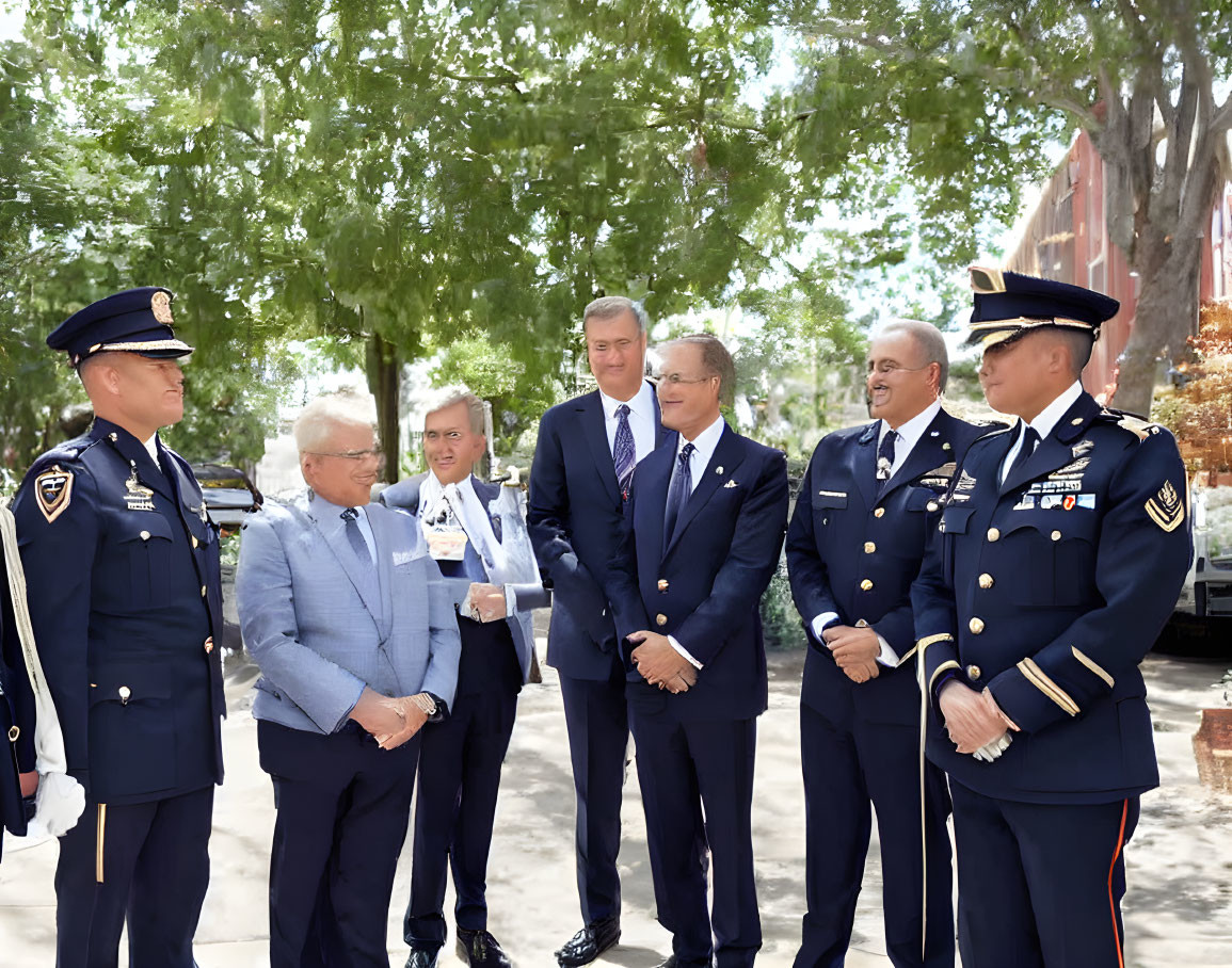 Men in military and civilian attire conversing outdoors under trees