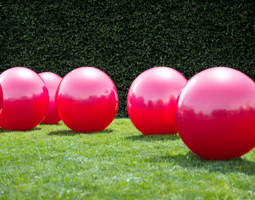 Vibrant red spheres on green lawn with shiny reflective surface