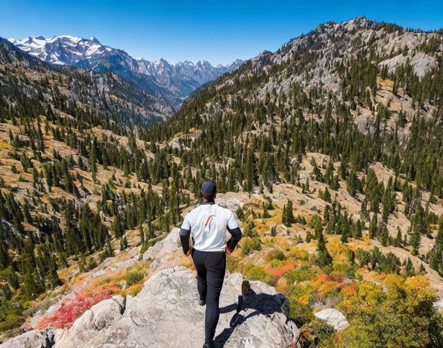 Person in white shirt gazes at scenic mountain landscape