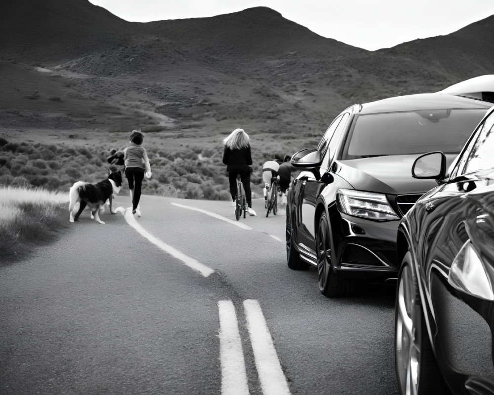 Monochrome scene: people, dog, car on road with hills