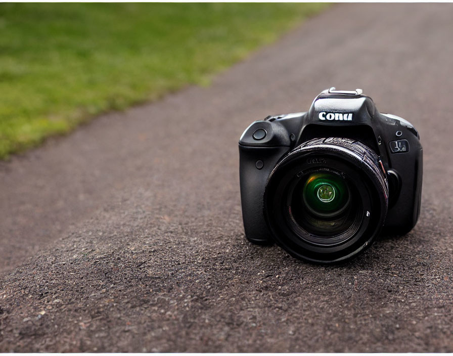 Branded lens DSLR camera on asphalt path with grass background