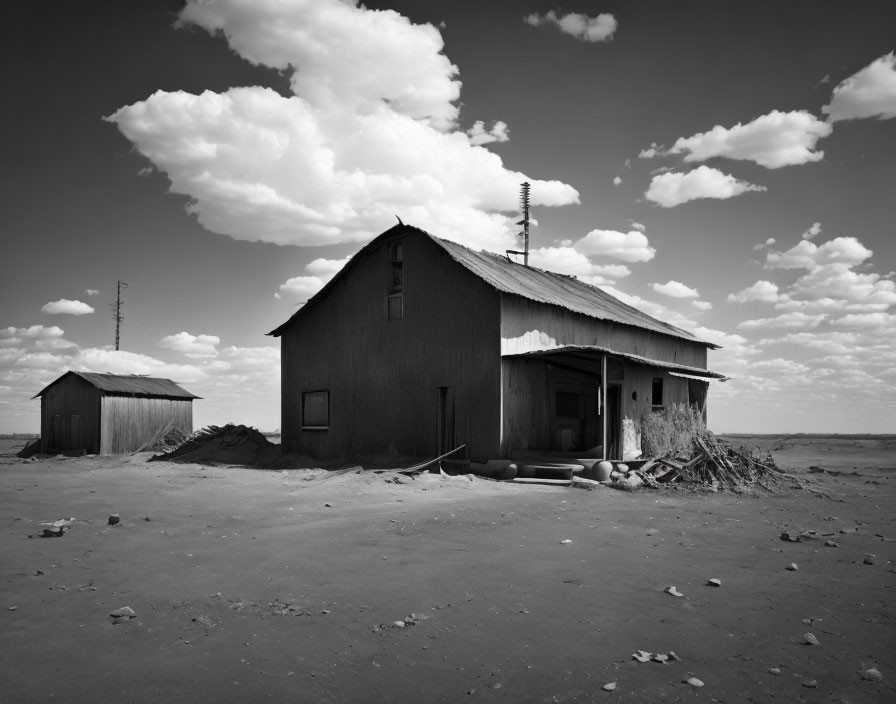 Monochrome image: abandoned wooden structures in barren landscape