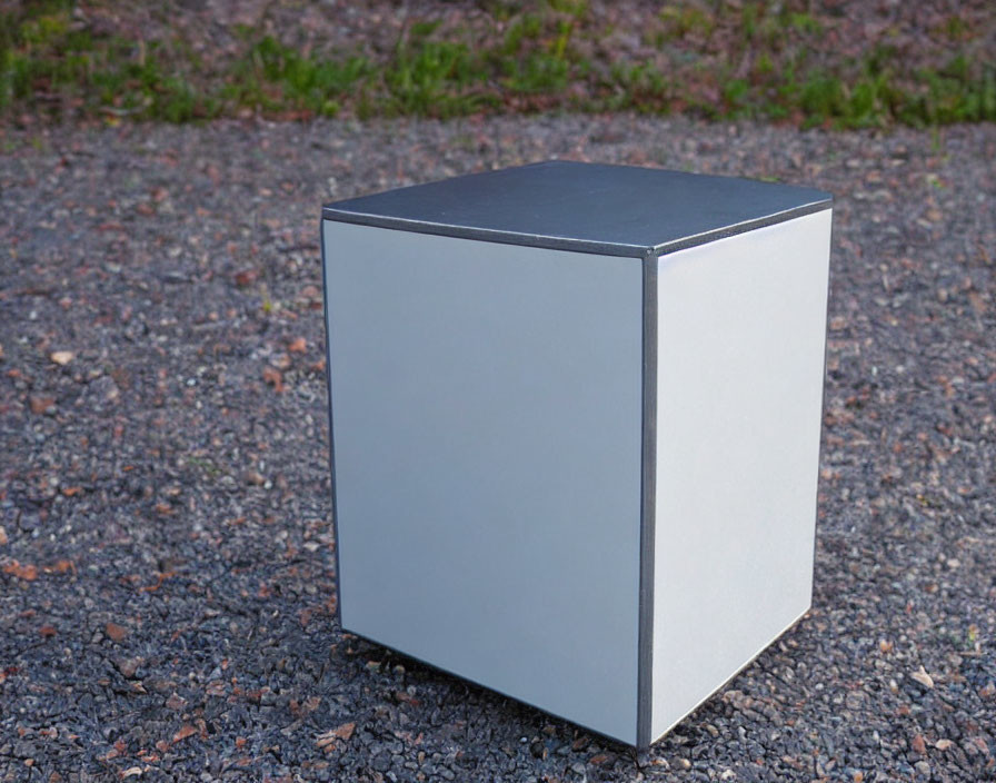 Reflective Silver Cube on Asphalt Ground with Stones