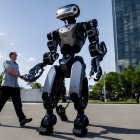 Man interacting with large bipedal robot in sunny urban setting