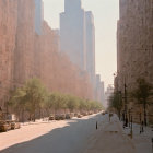 City street with large buildings, trees, and hazy sky