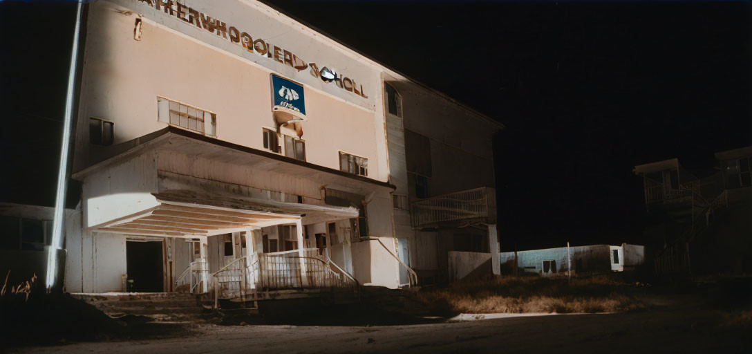 Dilapidated two-story motel building at night with vacancy sign