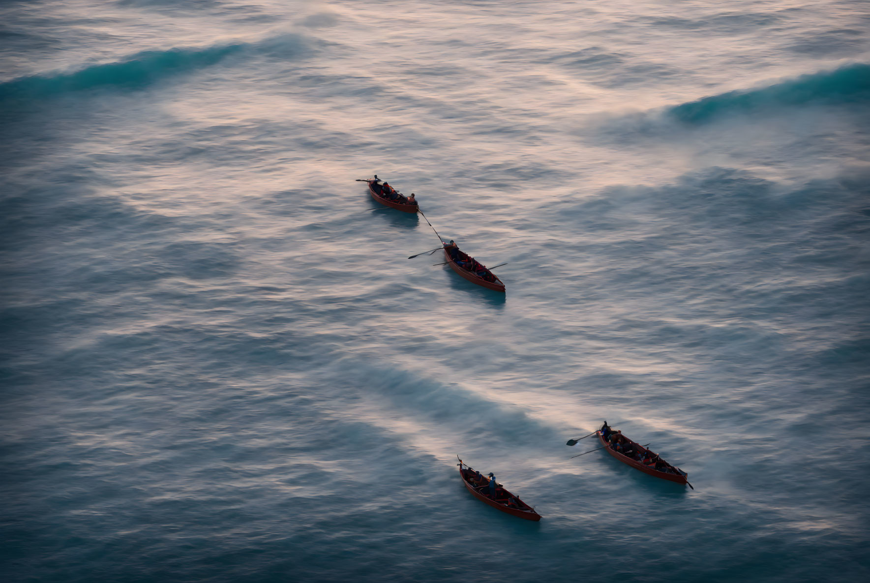 Rowers on Three Boats Creating Wake Patterns on Blue Water at Golden Hour