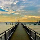 Symmetrical pier and yachts in tranquil sunset seascape