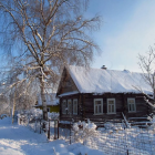 Snow-covered cottage with glowing windows in winter landscape